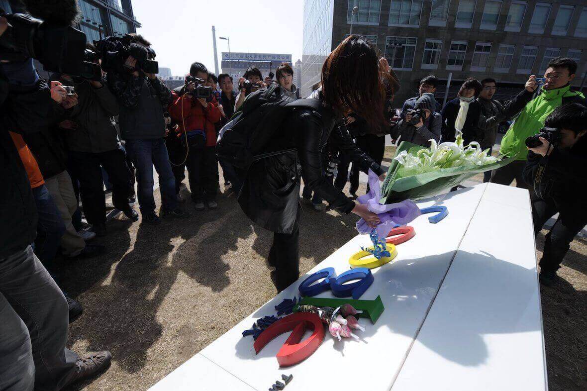 Eine Frau legt Blumen auf das Schild für Googles Büros in China